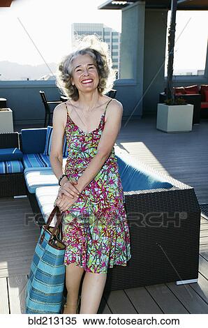 Stock Photography - Caucasian woman holding purse on urban rooftop. Fotosearch