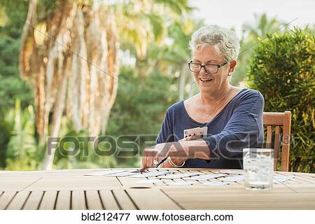 Stock Photo - Caucasian woman playing cards outdoors. Fotosearch