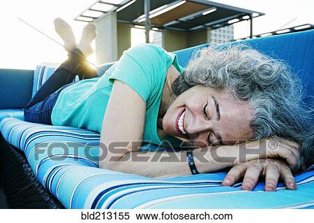 Stock Photography - Caucasian woman relaxing on sofa on urban rooftop. Fotosearch