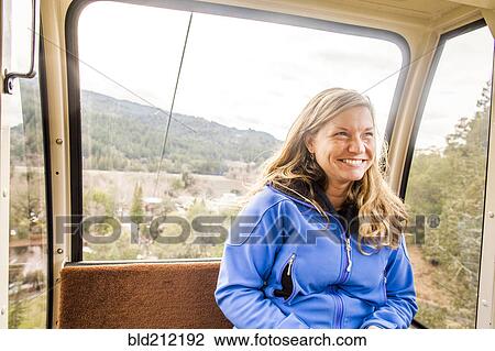 Stock Image - Caucasian woman riding in aerial tram. Fotosearch