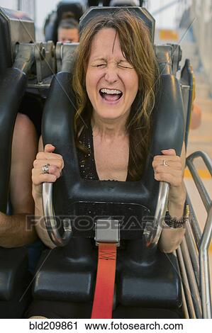 Stock Image - Caucasian woman shouting on roller coaster. Fotosearch