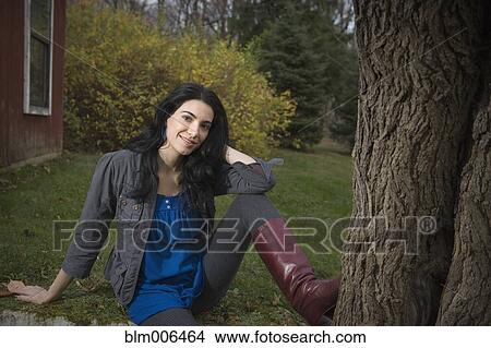 Caucasian woman sitting in yard near tree View Large Photo Image Picture - Caucasian woman sitting in yard near tree. Fotosearch