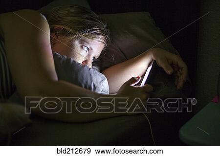 Caucasian woman using cell phone in bed View Large Photo Image Stock Photo - Caucasian woman using cell phone in bed. Fotosearch