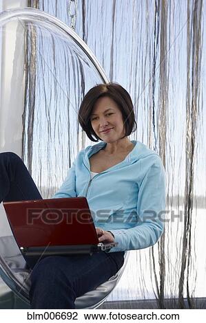 Caucasian woman using laptop in modern chair View Large Photo Image Stock Image - Caucasian woman using laptop in modern chair. Fotosearch