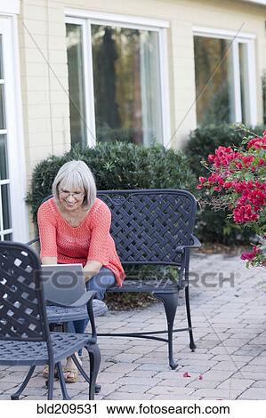 Stock Image - Caucasian woman using laptop outdoors. Fotosearch