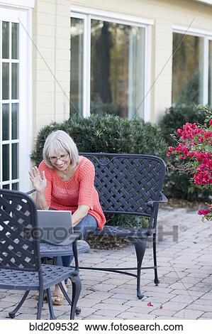Stock Image - Caucasian woman using laptop outdoors. Fotosearch