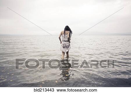 Caucasian woman wading in water on beach View Large Photo Image Stock Image - Caucasian woman wading in water on beach. Fotosearch