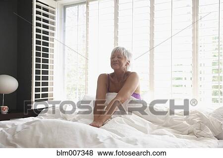 Stock Photo - Caucasian woman waking in bed. Fotosearch