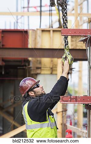 Caucasian worker holding hook at construction site View Large Photo Image Stock Image - Caucasian worker holding hook at construction site. Fotosearch