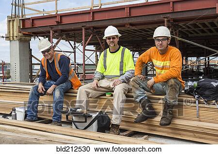 Stock Image - Caucasian workers smiling at construction site. Fotosearch