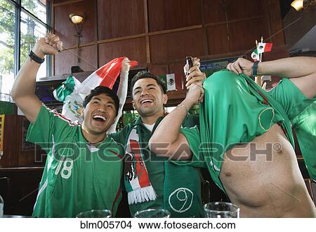 Cheering Hispanic men watching television in sports bar View Large Photo Image Picture - Cheering Hispanic men watching television in sports bar. Fotosearch