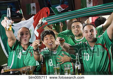 Stock Image - Cheering men drinking in sports bar. Fotosearch