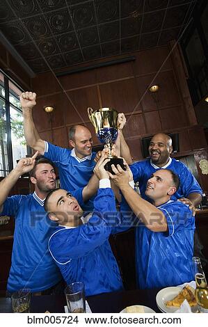 Cheering teammates and man lifting trophy View Large Photo Image Picture - Cheering teammates and man lifting trophy. Fotosearch