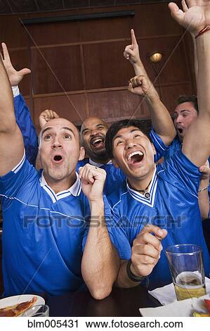 Cheering teammates watching television in sports bar View Large Photo Image Stock Image - Cheering teammates watching television in sports bar. Fotosearch