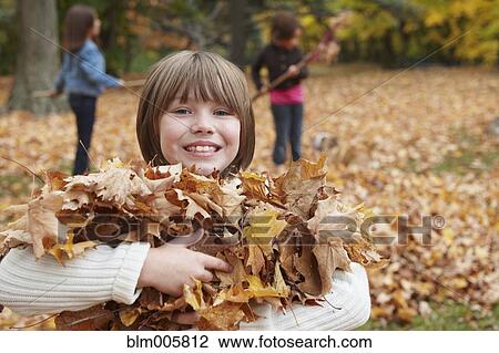 Stock Image - Children raking autumn leaves. Fotosearch