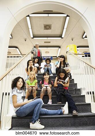 Stock Image - Children sitting on library staircase. Fotosearch