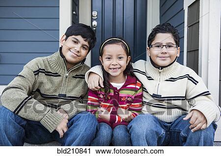 Stock Image - Children smiling together on front stoop. Fotosearch