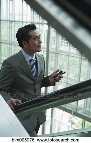 Stock Photograph - Chinese businessman on escalator. Fotosearch
