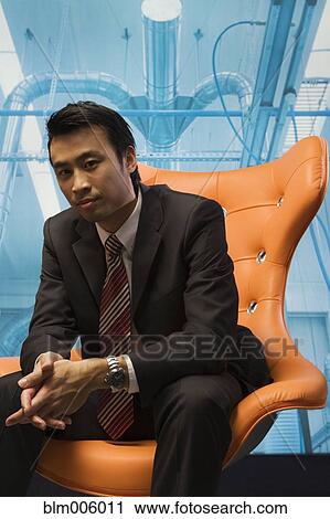 Stock Image - Chinese businessman sitting in chair. Fotosearch