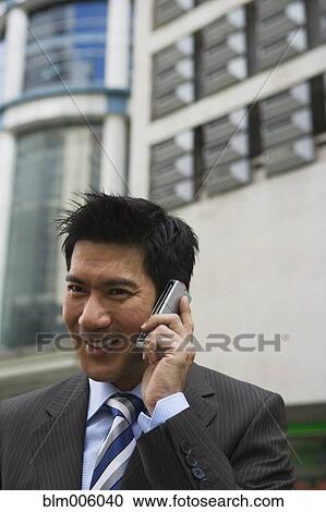 Stock Image - Chinese businessman talking on cell phone. Fotosearch