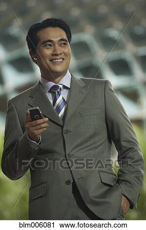 Chinese businessman talking on cell phone with hands-free device View Large Photo Image Stock Image - Chinese businessman talking on cell phone with hands-free device. Fotosearch