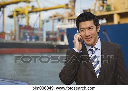 Chinese businessman talking on cell phone in shipyard View Large Photo Image Stock Photo - Chinese businessman talking on cell phone in shipyard. Fotosearch