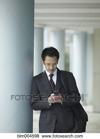 Chinese businessman text messaging on cell phone View Large Photo Image Stock Photo - Chinese businessman text messaging on cell phone. Fotosearch