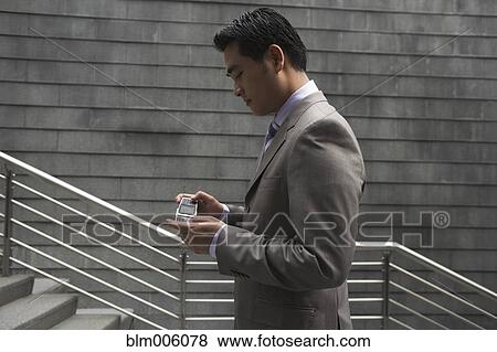 Chinese businessman text messaging on cell phone View Large Photo Image Stock Photo - Chinese businessman text messaging on cell phone. Fotosearch