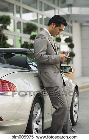 Stock Photography - Chinese businessman text messaging on cell phone. Fotosearch