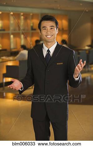 Stock Image - Chinese businessman welcoming guests to bar. Fotosearch