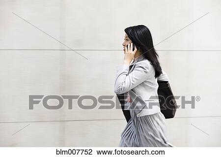 Chinese businesswoman walking and talking on cell phone View Large Photo Image Stock Image - Chinese businesswoman walking and talking on cell phone. Fotosearch