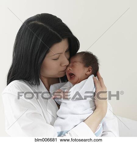 Stock Image - Chinese mother hugging newborn baby girl. Fotosearch