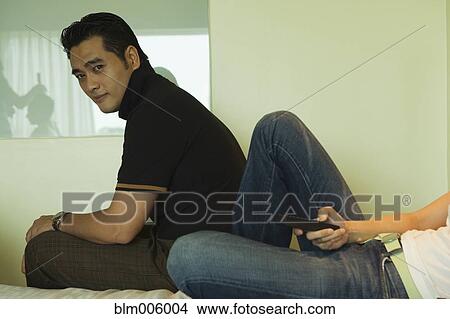 Chinese woman watching television in bed with husband View Large Photo Image Picture - Chinese woman watching television in bed with husband. Fotosearch