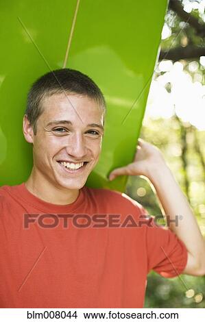 Close up of Caucasian teenage boy smiling and holding surfboard View Large Photo Image Picture - Close up of Caucasian teenage boy smiling and holding surfboard. Fotosearch