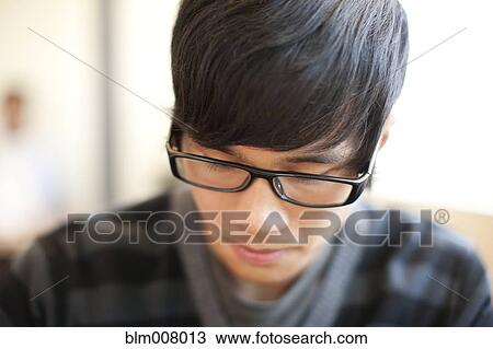 Stock Image - Close up of mixed race man with eyeglasses looking down. Fotosearch