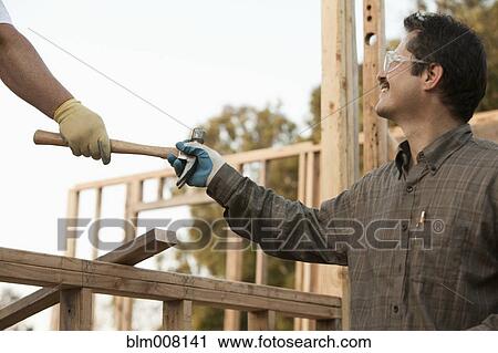 Co-worker handing mixed race construction worker a hammer View Large Photo Image Stock Image - Co-worker handing mixed race construction worker a hammer. Fotosearch