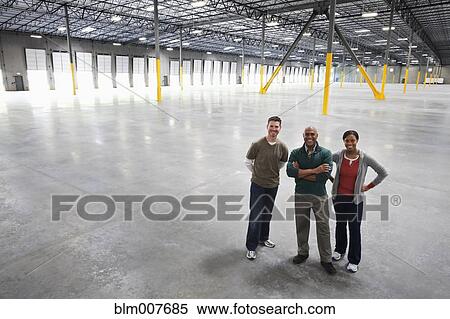 Co-workers standing in empty warehouse View Large Photo Image Stock Photography - Co-workers standing in empty warehouse. Fotosearch