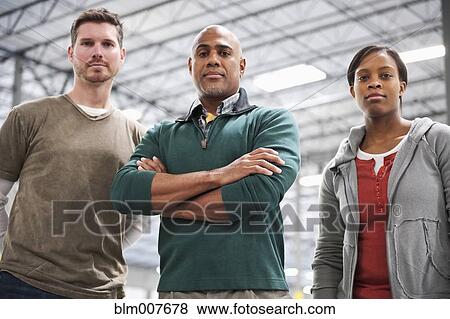 Stock Photo - Co-workers standing in warehouse. Fotosearch