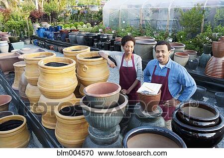 Stock Image - Co-workers working in garden nursery. Fotosearch