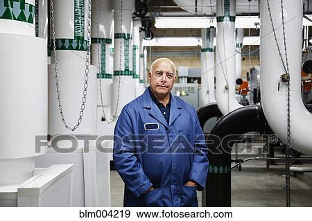 Confident technician standing in industrial plant View Large Photo Image Stock Photo - Confident technician standing in industrial plant. Fotosearch