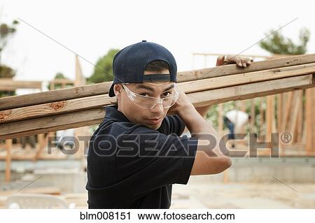 Stock Image - Construction worker carrying lumber. Fotosearch