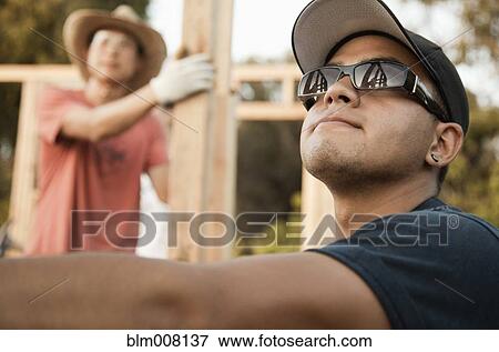 Construction workers adjusting house frame View Large Photo Image Stock Photo - Construction workers adjusting house frame. Fotosearch