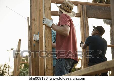Construction workers adjusting house frame View Large Photo Image Stock Photograph - Construction workers adjusting house frame. Fotosearch