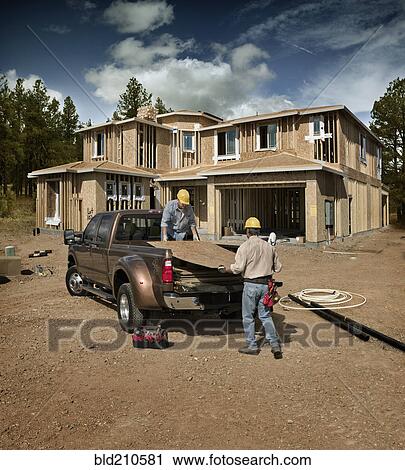 Construction workers carrying plywood on site View Large Photo Image Stock Image - Construction workers carrying plywood on site. Fotosearch