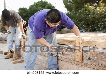 Stock Photography - Construction workers hammering lumber. Fotosearch