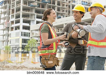 Stock Photo - Construction workers on construction site drinking coffee. Fotosearch