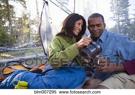 Stock Photography - Couple camping and cuddling in tent with coffee. Fotosearch