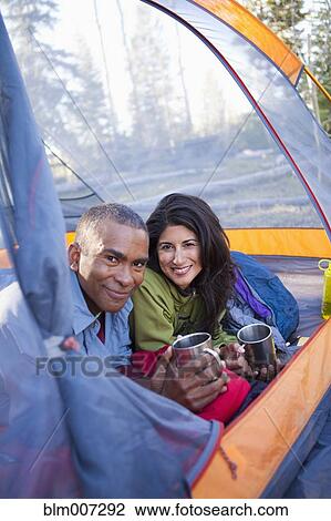 Stock Image - Couple camping and laying in tent. Fotosearch