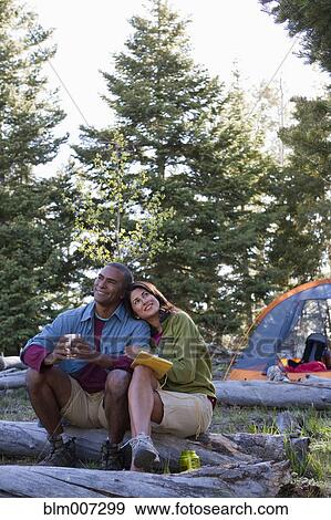 Couple camping and sitting on log View Large Photo Image Stock Photo - Couple camping and sitting on log. Fotosearch