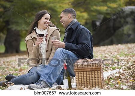 Stock Photo - Couple drinking red wine in park. Fotosearch